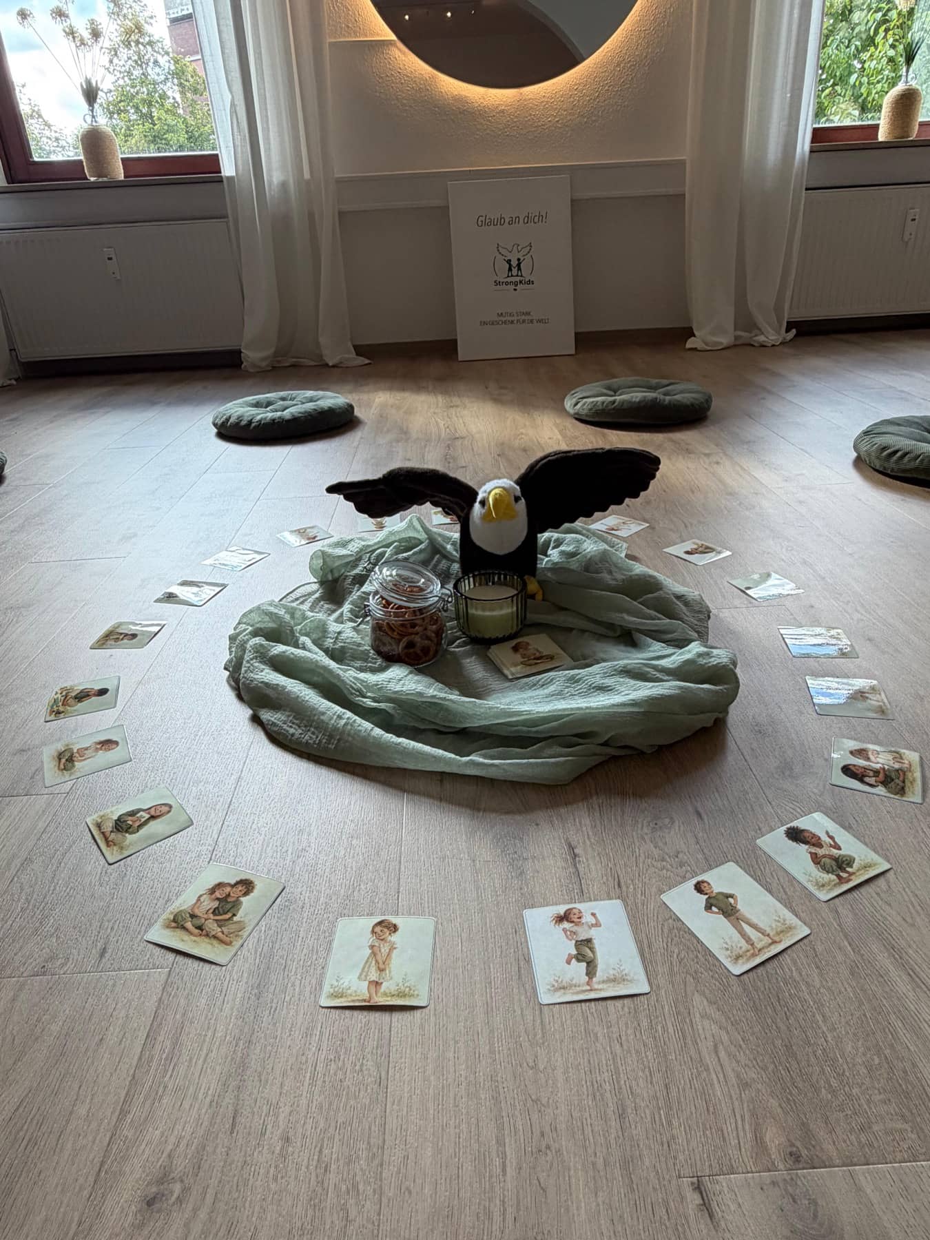 Adler Ari sitzt im Mattenkreis von StrongKids Weyhe, umgeben von Bildkarten
