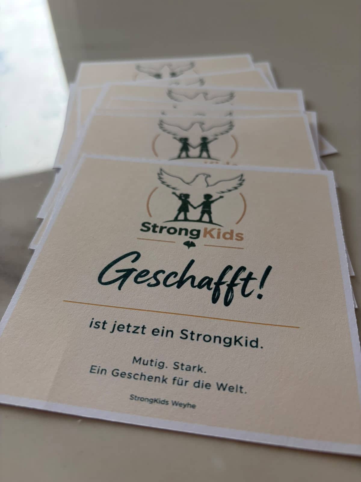 Karten mit StrongKids-Logo und der Aufschrift: Geschafft! … ist jetzt ein StrongKid.